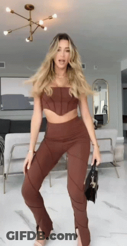 Woman Standing In Brown Top And Pants GIF
