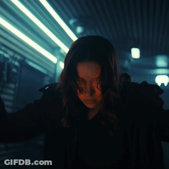 Woman Standing In Dark Room With Lights Behind Her GIF