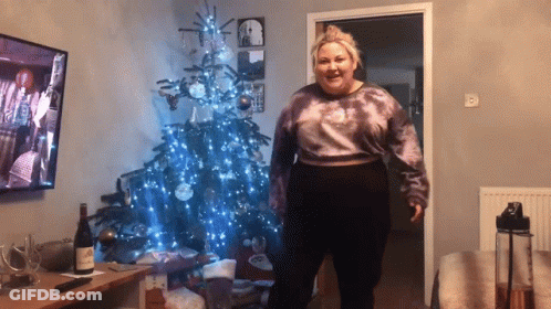 Woman Standing In Front Of Christmas Tree With Wine GIF