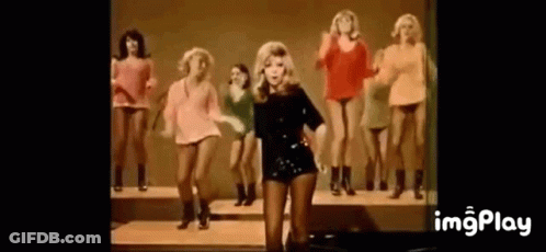 Woman Standing In Front Of Dancing Women GIF