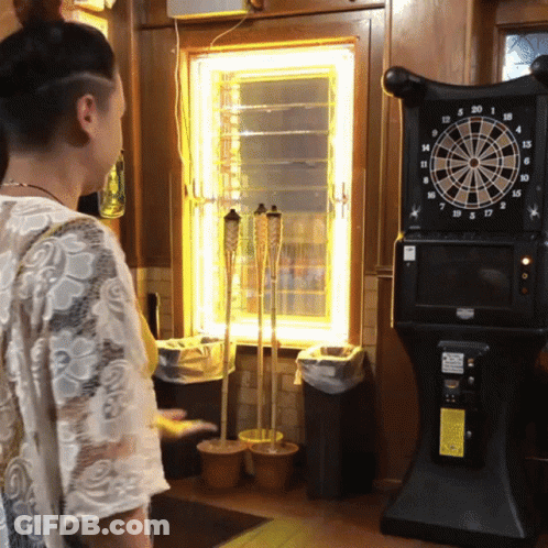 Woman Standing In Front Of Dart Board GIF