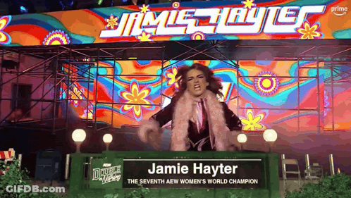 Woman Standing In Front Of Jamie Hayter Sign GIF