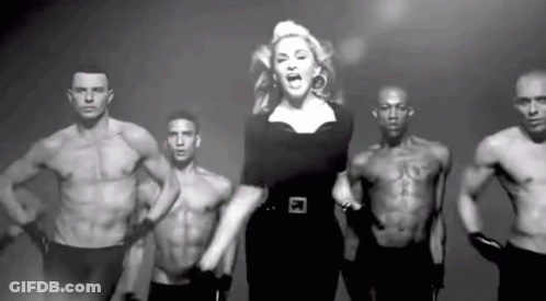 Woman Standing In Front Of Shirtless Muscular Men GIF