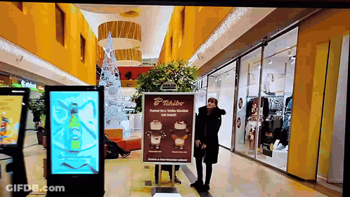 Woman Standing In Front Of Tchibo Sign GIF