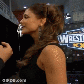 Woman Standing In Front Of Wrestle Sign GIF