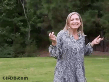 Woman Standing In Grassy Field With Arms Outstretched Smiling GIF
