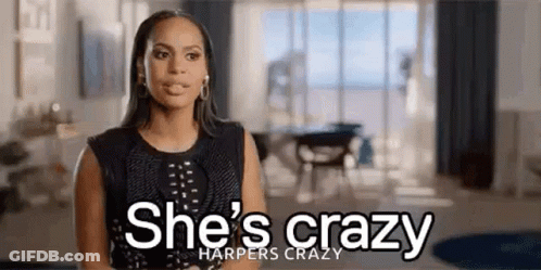 Woman Standing In Living Room With She's Crazy Sign GIF