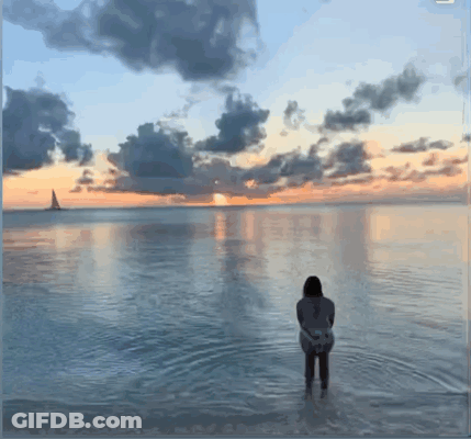 Woman Standing In Water At Sunset GIF