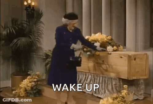 Woman Standing Next To Coffin Says Wake Up GIF