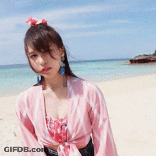 Woman Standing On Beach In Pink Shirt GIF