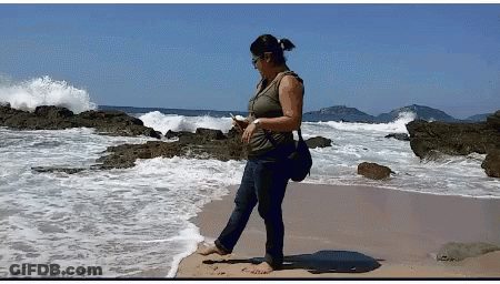 Woman Standing On Beach Looking At Phone GIF