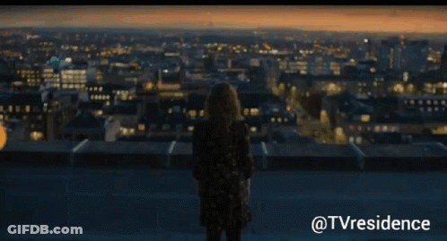 Woman Standing On Rooftop Over City GIF