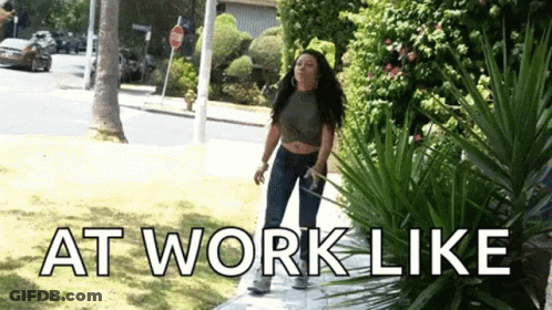 Woman Standing On Sidewalk Next To Bush Saying At Work Like GIF
