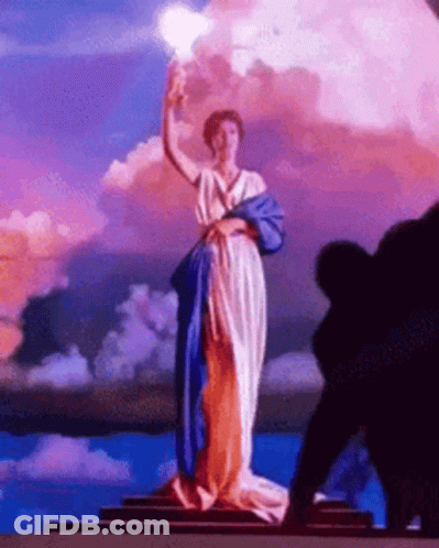 Woman Statue In Blue And White Dress Holding Torch GIF