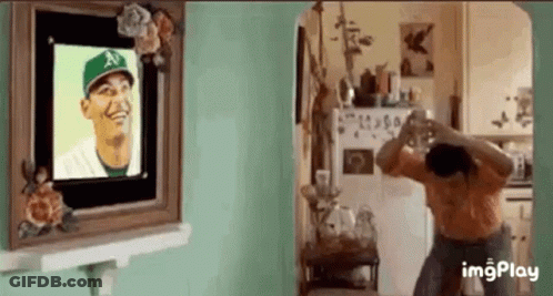 Woman Taking Picture Of Man In Baseball Cap In Front Of Picture Frame GIF