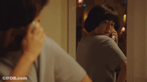 Woman Talking On Phone Looking In Mirror GIF