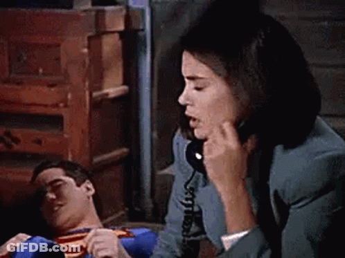 Woman Talking On Phone While Superman Lies On Floor GIF
