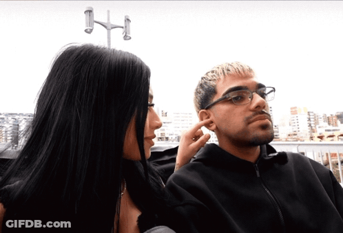 Woman Touching Man's Ear While He Looks At Her GIF