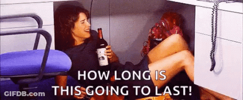 Woman Under Desk Holding Wine Saying How Long Is This Going To Last GIF
