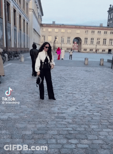 Woman Walking Cobblestone Street GIF