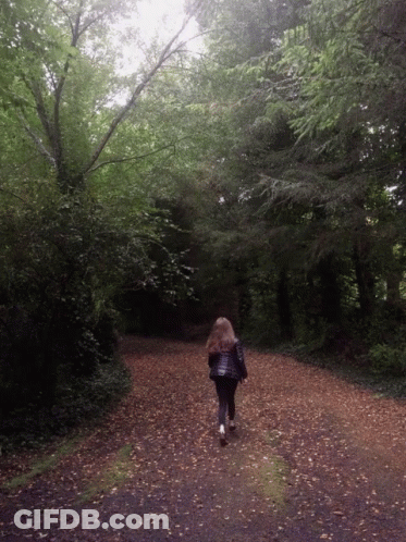Woman Walking Down Dirt Road In Woods GIF