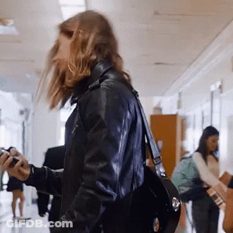 Woman Walking Down Hallway Holding Camera GIF