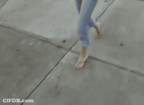 Woman Walking Down Sidewalk Carrying Books And Purse GIF