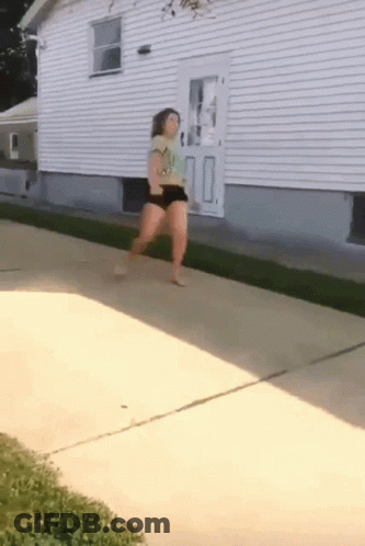 Woman Walking On Sidewalk Near House GIF