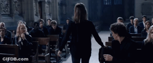 Woman Walking Through Church With People In Pews GIF