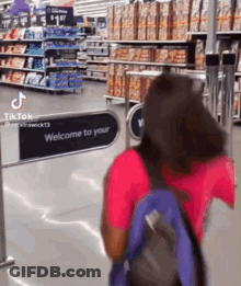 Woman Walking Through Grocery Store With Welcome Sign GIF