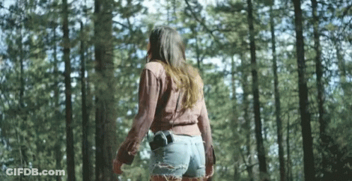 Woman Walking Through Woods With Gun In Pocket GIF