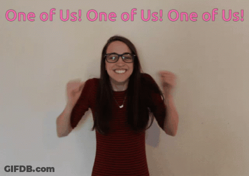 Woman Wearing Glasses In Front Of One Of Us Sign GIF