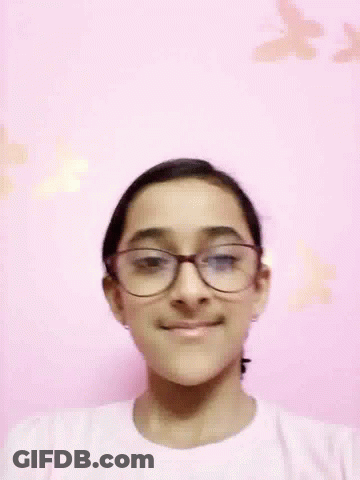 Woman Wearing Glasses Smiling In Front Of Pink Wall With Butterflies GIF