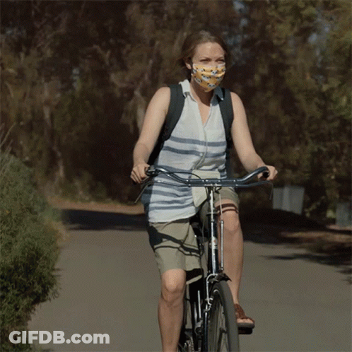 Woman Wearing Mask Rides Bike Down Road GIF
