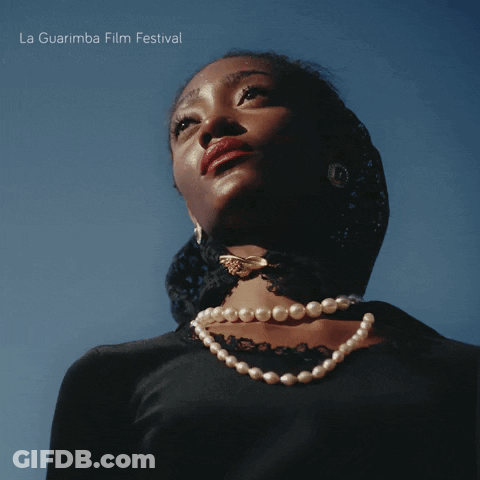 Woman Wearing Pearl Necklace Looking At La Guarimba Poster GIF