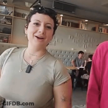 Woman With Arm Tattoo Smiling In Front Of How Wonderful Wall GIF