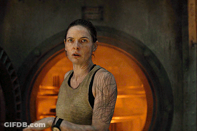 Woman With Arm Tattoo Standing In Front Of Orange Door GIF