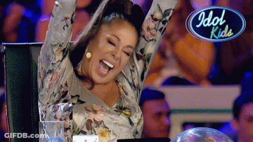 Woman With Arms In Air Sitting In Front Of Idol Kids Logo GIF