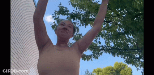 Woman With Arms Outstretched In Front Of Tree GIF