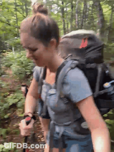 Woman With Backpack Walking Through Forest GIF