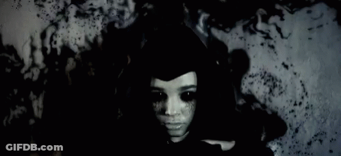 Woman With Black Eyes And Black Hat In Dark Room GIF