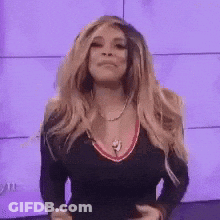 Woman With Blonde Hair, Black Top, Necklace, Purple Wall GIF