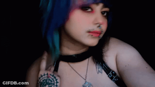 Woman With Blue Hair And Piercings Taking Selfie With Bat Necklace GIF