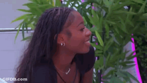 Woman With Braids And Plant Looking At Camera GIF