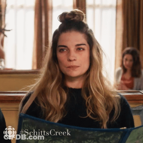 Woman With Bun Holding Schitt's Creek Book GIF