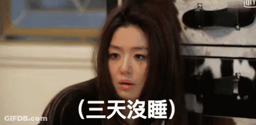 Woman With Bun Sitting In Front Of Suitcase With Chinese Writing GIF