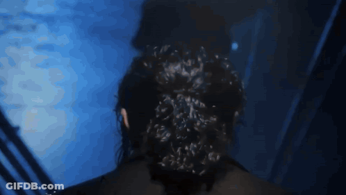 Woman With Bun Standing In Dark Room GIF