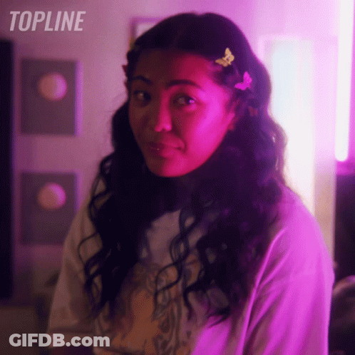 Woman With Butterfly In Hair Standing In Front Of Topline Sign GIF
