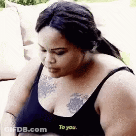 Woman With Chest Tattoo Sitting On Couch GIF