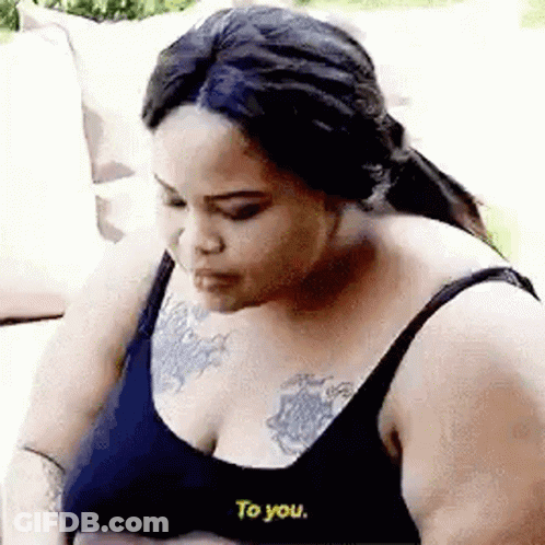 Woman With Chest Tattoo Talking On Couch GIF